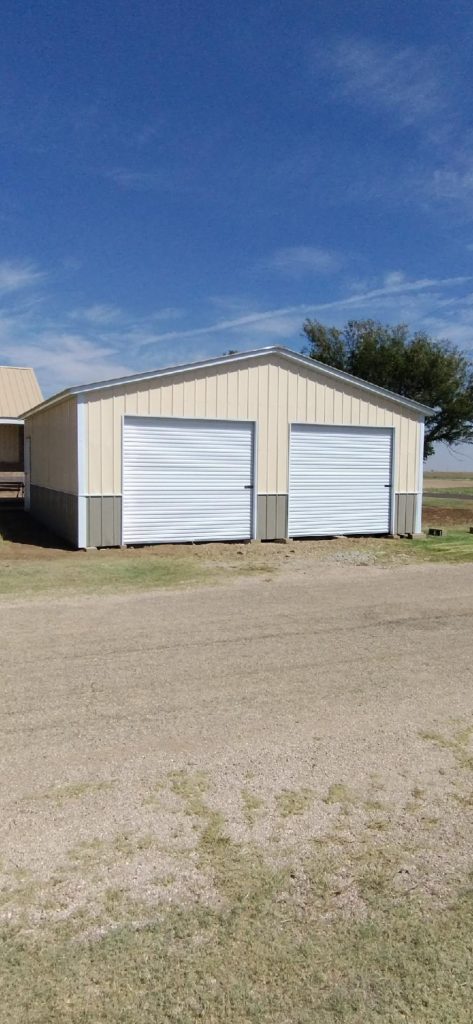 Beige metal garage with two white roll-up doors and matching trim