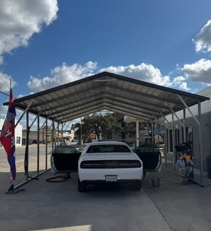 Metal carport shading a vehicle at a commercial storefront