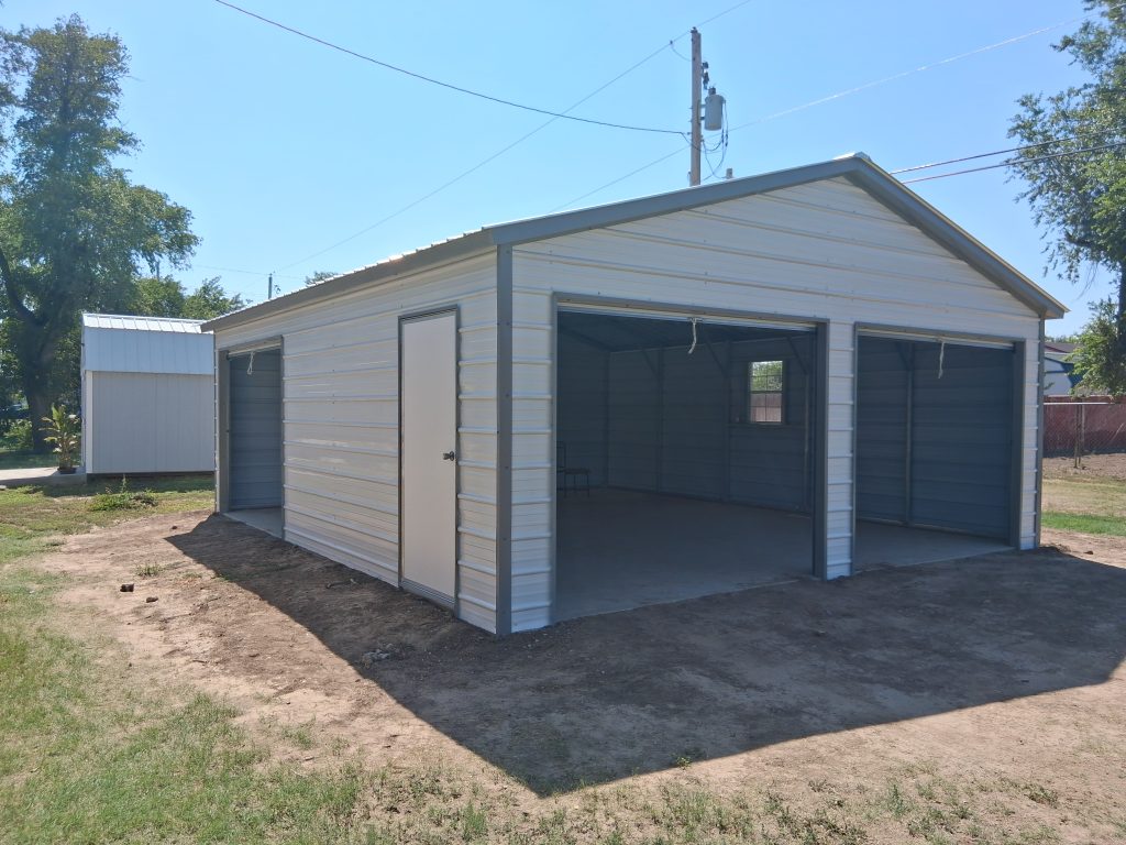 Cream and gray fully enclosed garage with roll-up doors, man door, and window